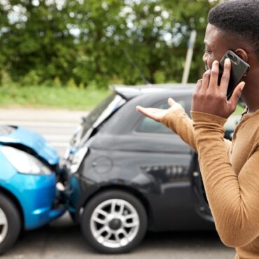 man-holding-phone-in-car-accident-resize.jpg